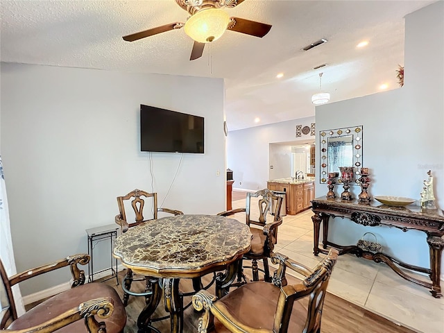 dining area featuring ceiling fan, lofted ceiling, a textured ceiling, and light hardwood / wood-style flooring