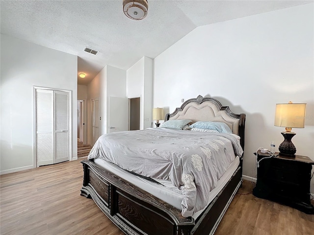 bedroom featuring a textured ceiling, vaulted ceiling, and light wood-type flooring