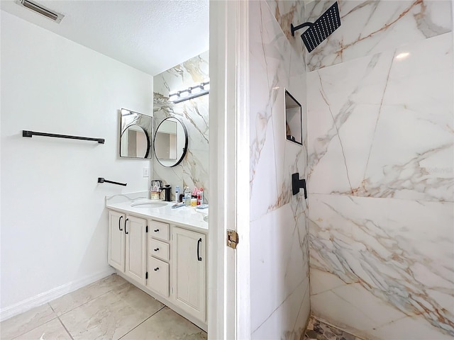 bathroom with vanity, a tile shower, and a textured ceiling