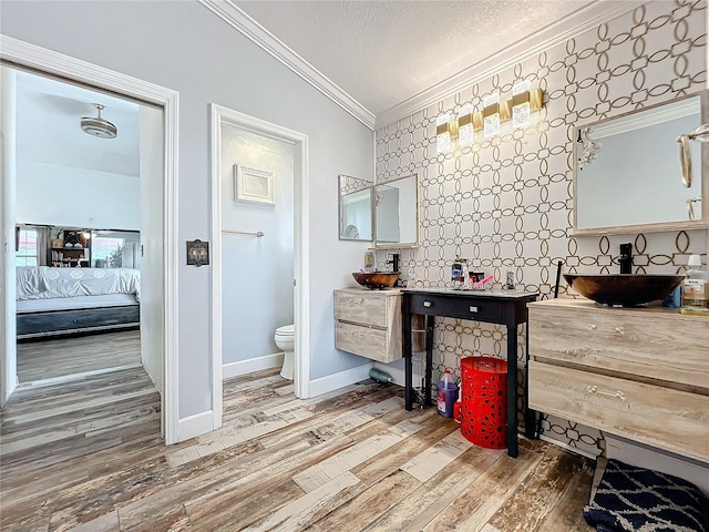 bathroom with hardwood / wood-style floors, crown molding, vaulted ceiling, toilet, and a textured ceiling