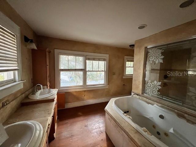 bathroom with a tub to relax in, vanity, and wood-type flooring