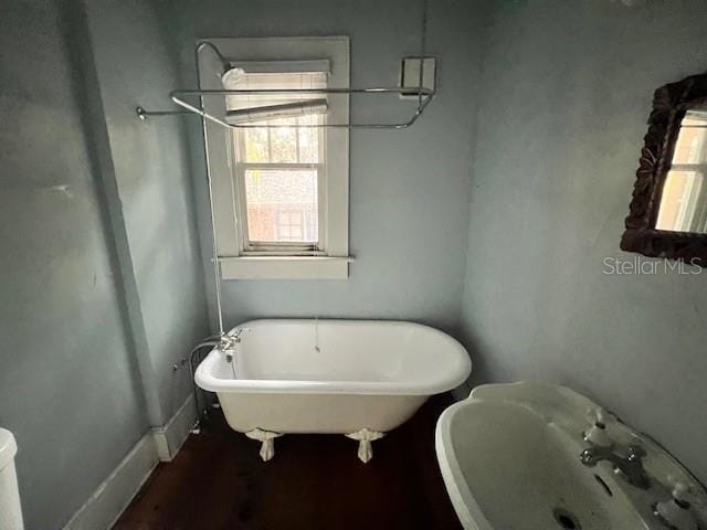 bathroom with toilet, a wealth of natural light, a bathing tub, and sink