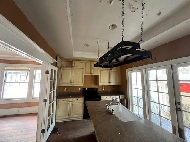 kitchen featuring french doors, sink, black electric range oven, dark hardwood / wood-style floors, and cream cabinetry