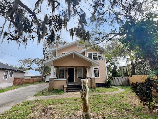 view of front of home with covered porch, fence, and driveway