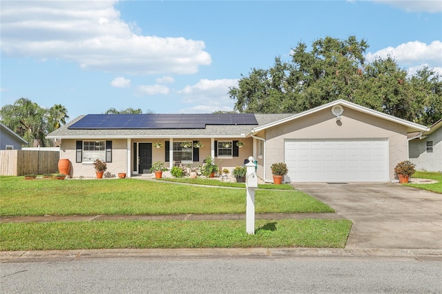 ranch-style house featuring roof mounted solar panels, driveway, a front lawn, and fence