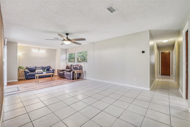 unfurnished living room with ceiling fan, light tile patterned flooring, and a textured ceiling