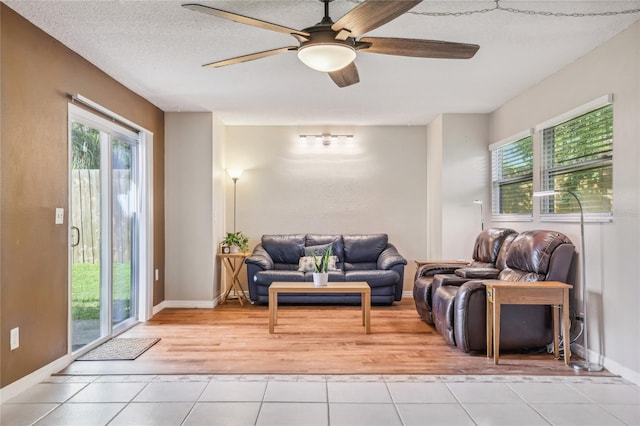 living room with ceiling fan, light tile patterned flooring, and a textured ceiling