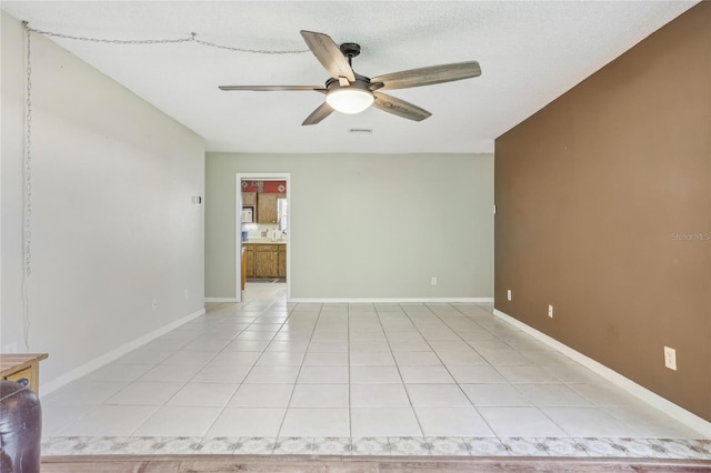 tiled empty room featuring a textured ceiling and ceiling fan