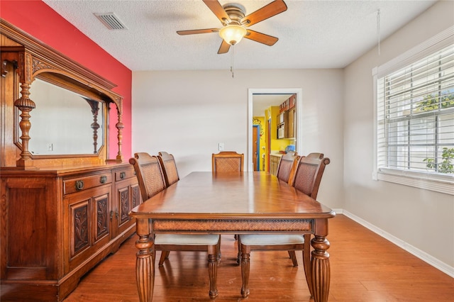 dining space featuring a textured ceiling, hardwood / wood-style flooring, and ceiling fan