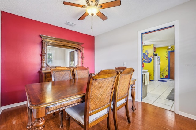 dining room with ceiling fan, light hardwood / wood-style flooring, and a textured ceiling