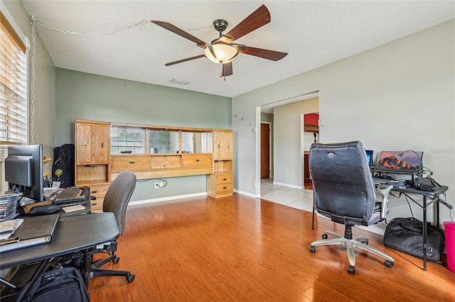 office with ceiling fan, light wood-type flooring, and a textured ceiling