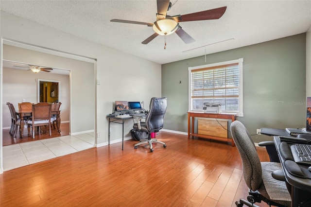 home office featuring a textured ceiling, light wood-type flooring, and ceiling fan