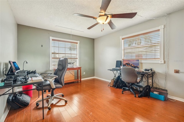 office space featuring ceiling fan, plenty of natural light, wood-type flooring, and a textured ceiling