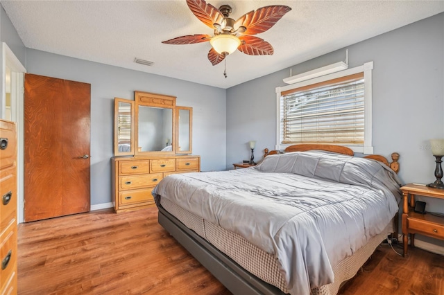 bedroom featuring wood-type flooring, a textured ceiling, and ceiling fan