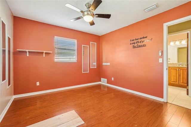 unfurnished room with ceiling fan, hardwood / wood-style floors, and a textured ceiling