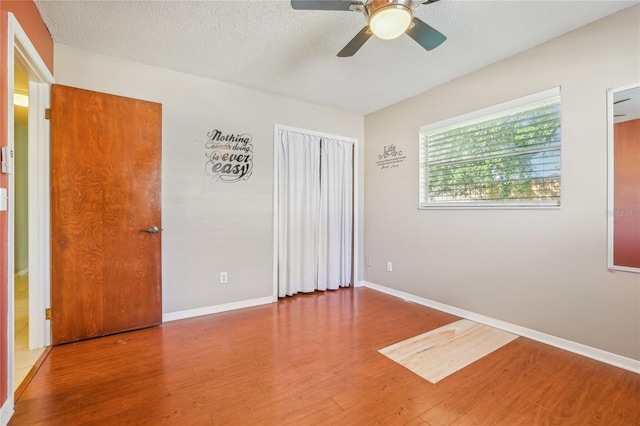 unfurnished room with ceiling fan, a textured ceiling, and hardwood / wood-style flooring