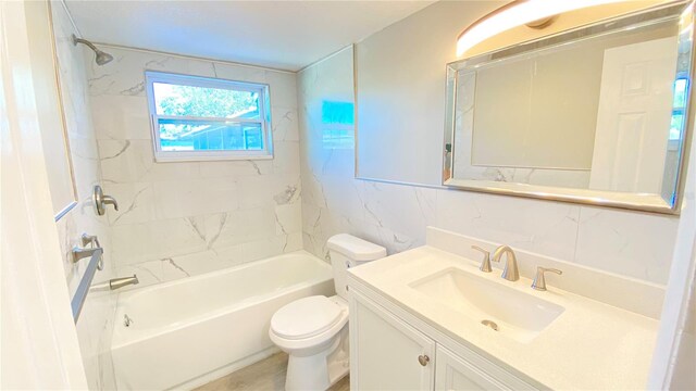 full bathroom with toilet, vanity, tile walls, and tiled shower / bath