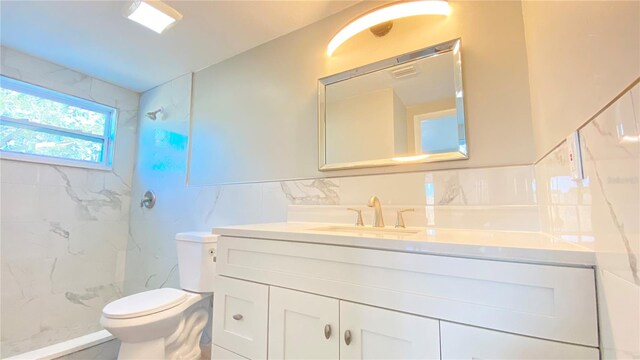 bathroom featuring tiled shower, vanity, tile walls, and toilet