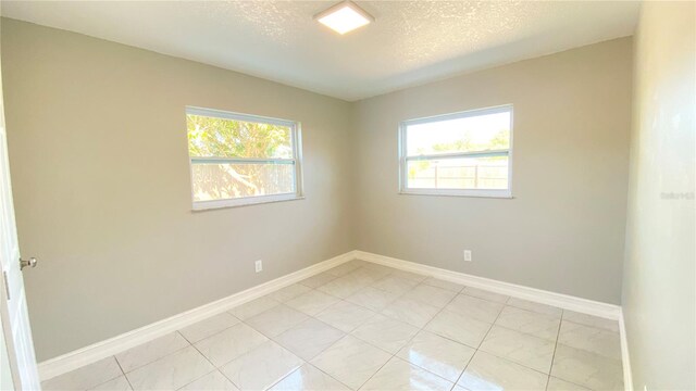 tiled spare room with a textured ceiling