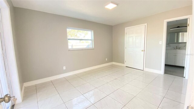 unfurnished bedroom featuring ensuite bathroom, sink, and light tile patterned flooring