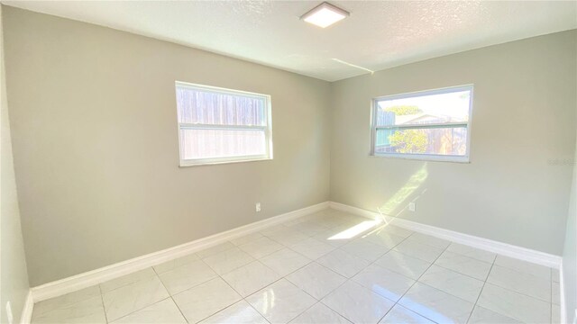 tiled empty room featuring a textured ceiling