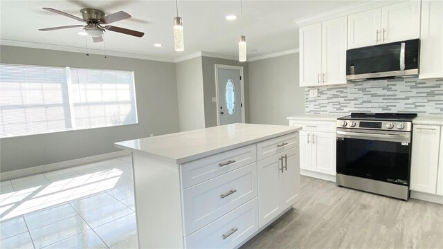 kitchen with crown molding, hanging light fixtures, white cabinets, and stainless steel appliances