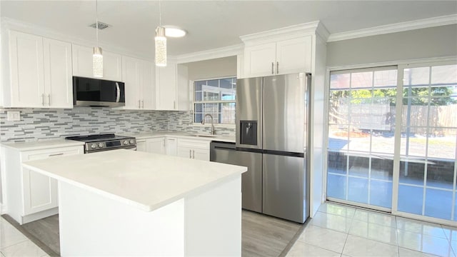 kitchen featuring crown molding, hanging light fixtures, appliances with stainless steel finishes, a kitchen island, and white cabinetry