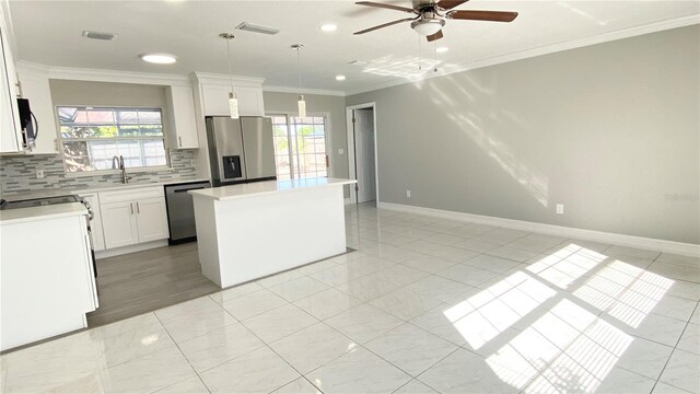 kitchen with a center island, white cabinets, pendant lighting, and appliances with stainless steel finishes