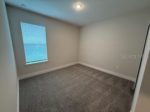 unfurnished room with dark carpet