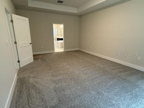 unfurnished room with a tray ceiling and dark carpet