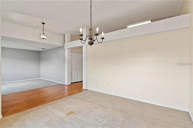 empty room with hardwood / wood-style floors and an inviting chandelier