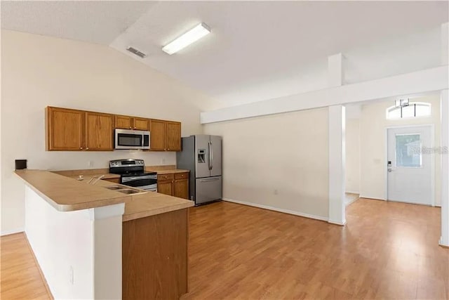 kitchen featuring kitchen peninsula, stainless steel appliances, sink, high vaulted ceiling, and light hardwood / wood-style floors