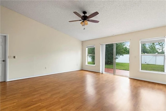 empty room featuring a textured ceiling, hardwood / wood-style flooring, vaulted ceiling, and ceiling fan