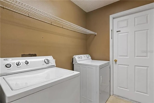 clothes washing area with a textured ceiling and washer and clothes dryer