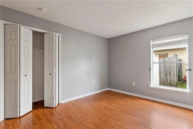 unfurnished bedroom featuring light hardwood / wood-style floors, a textured ceiling, and multiple windows