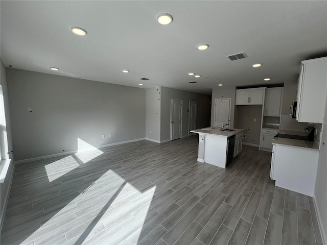 kitchen with open floor plan, visible vents, a center island with sink, and a sink