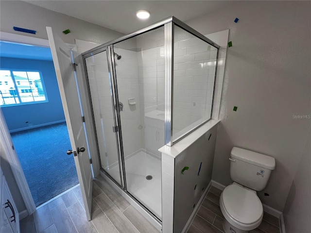 full bath featuring a stall shower, baseboards, toilet, and wood finish floors