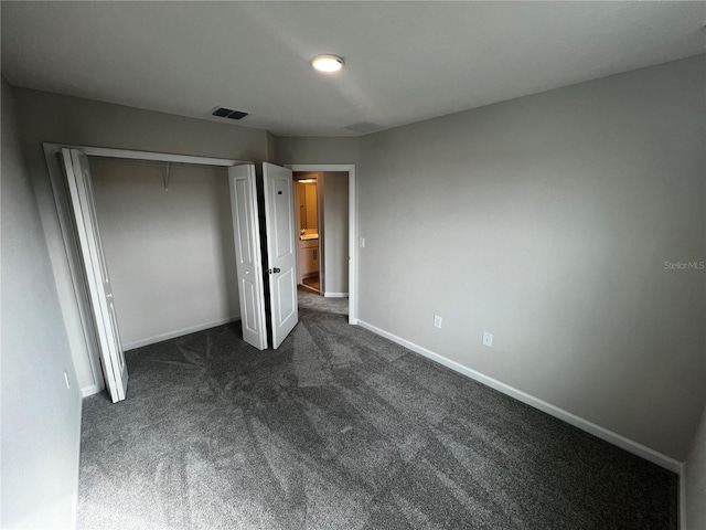 unfurnished bedroom featuring a closet, dark carpet, visible vents, and baseboards