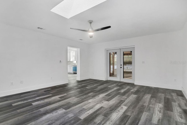 empty room with dark hardwood / wood-style floors, ceiling fan, a skylight, and french doors