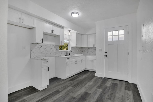 kitchen with white cabinetry, sink, dark hardwood / wood-style floors, backsplash, and a textured ceiling