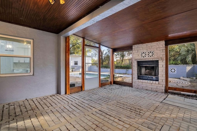 unfurnished sunroom featuring wooden ceiling and a fireplace