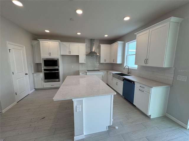 kitchen featuring white cabinets, appliances with stainless steel finishes, a kitchen island, and wall chimney range hood