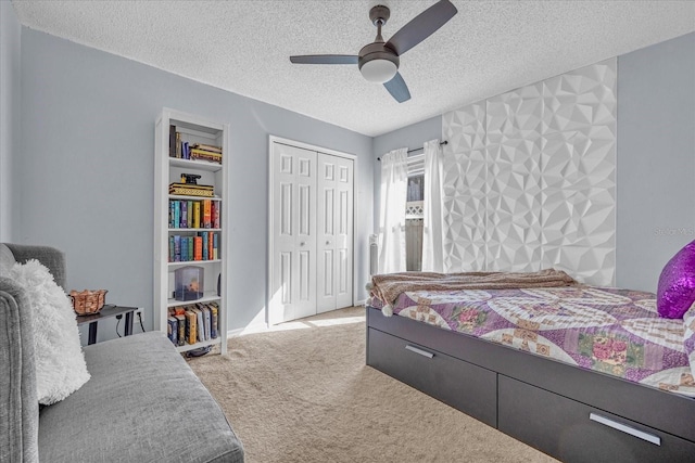 bedroom featuring a closet, a textured ceiling, light colored carpet, and ceiling fan