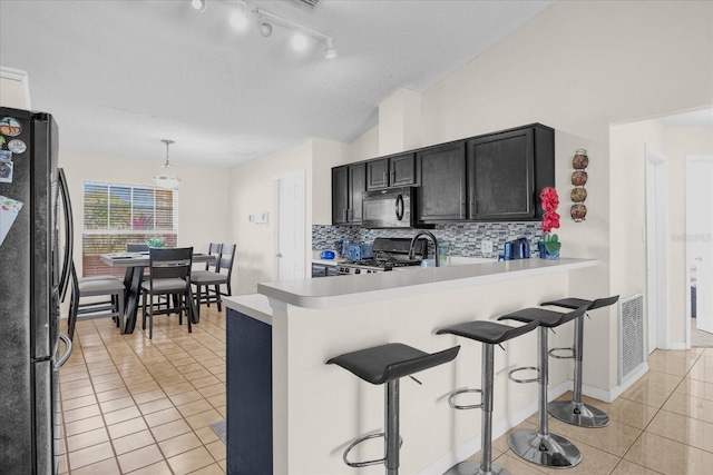 kitchen featuring a kitchen bar, kitchen peninsula, pendant lighting, and black appliances