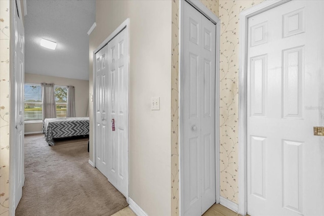 hallway featuring light colored carpet and a textured ceiling