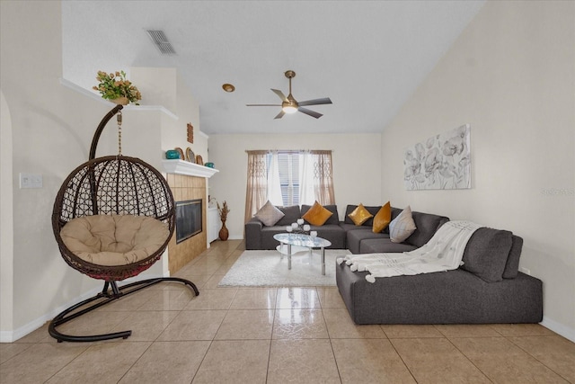 living room with ceiling fan, light tile patterned flooring, a fireplace, and vaulted ceiling