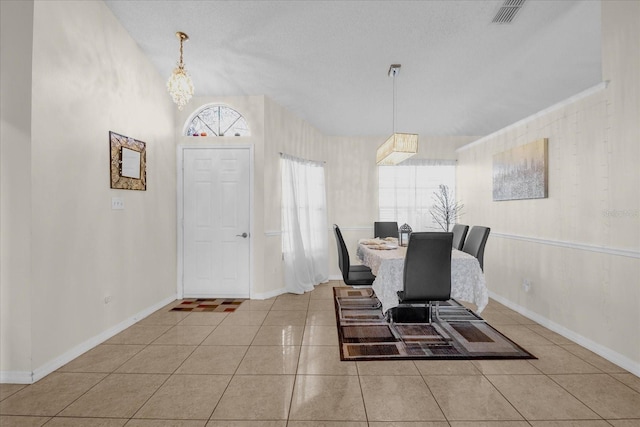 dining space with a notable chandelier, light tile patterned flooring, and a textured ceiling