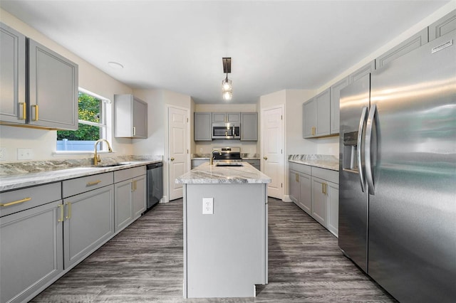 kitchen with sink, dark hardwood / wood-style flooring, gray cabinets, a kitchen island with sink, and appliances with stainless steel finishes