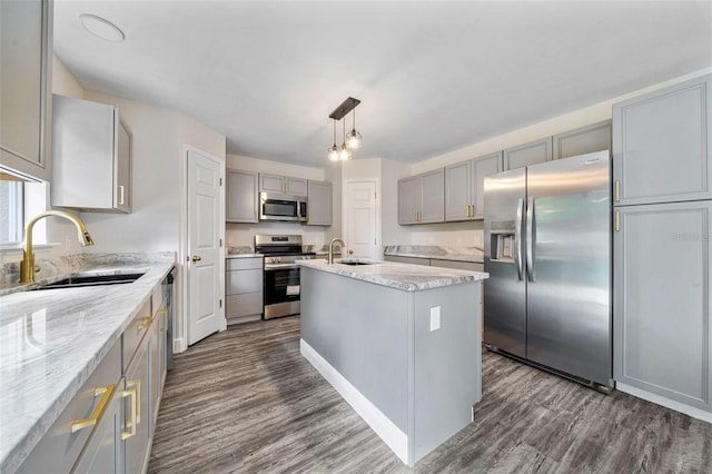 kitchen with appliances with stainless steel finishes, sink, dark hardwood / wood-style floors, and an island with sink