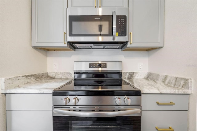 kitchen featuring appliances with stainless steel finishes, gray cabinets, and light stone counters